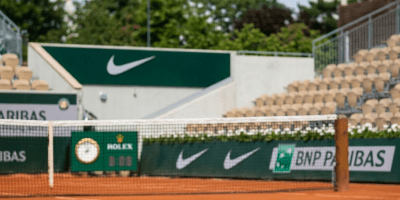 Female tennis player striking ball with forehand on clay court